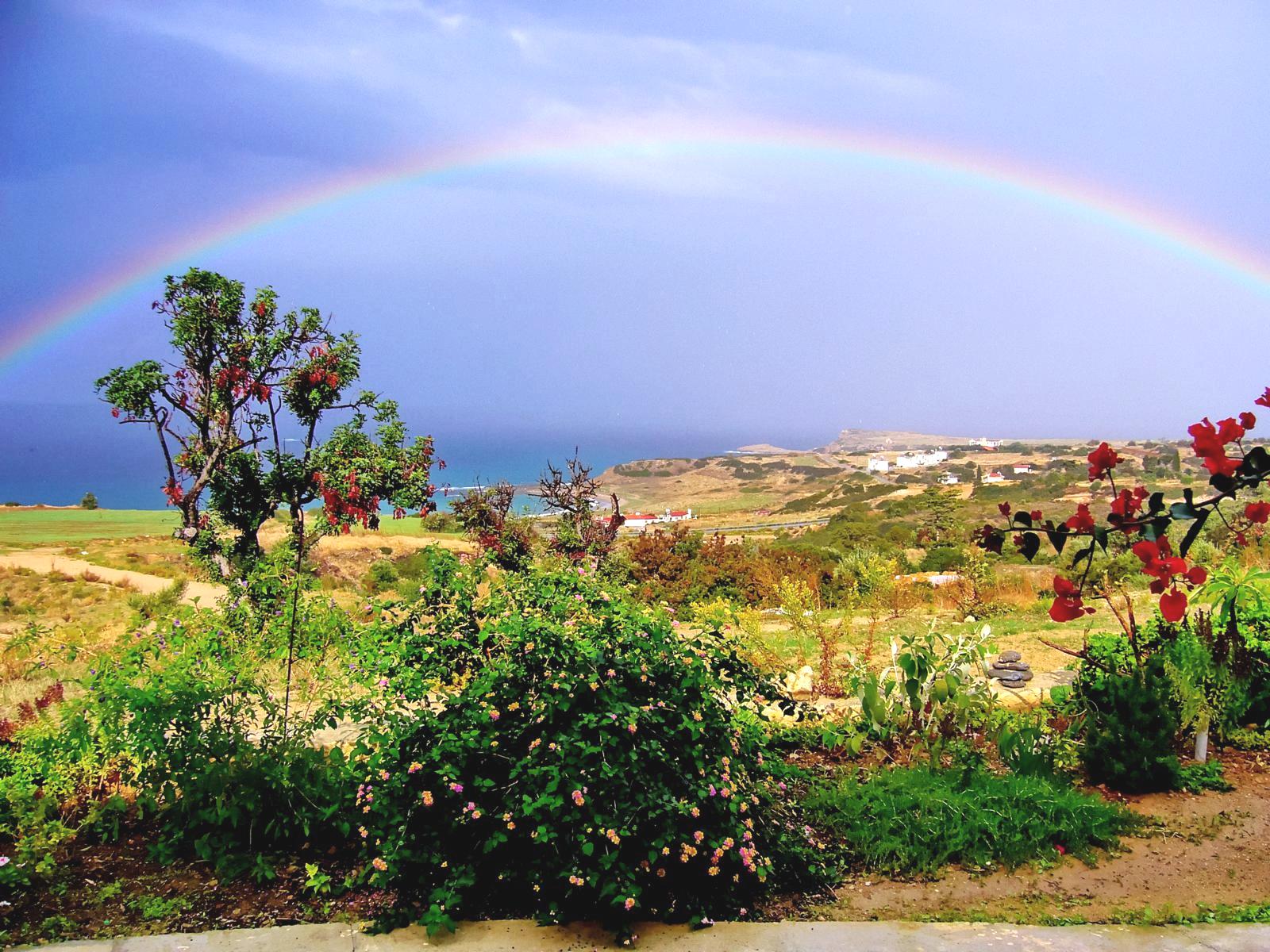 Ausblick auf die Kste und das azurblaue Meer mit einem Regenbogen - Lupe Reisen